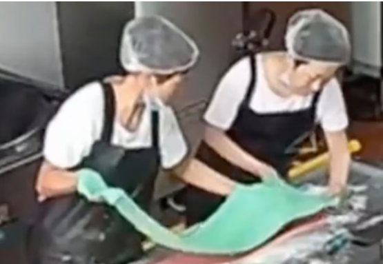 Captura de pantalla de una cámara de seguridad que muestra al personal de cocina añadiendo colorante a la harina. (Weibo)
